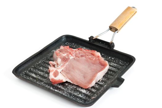 raw pork chop on a griddle with salt isolated on white background with clipping path