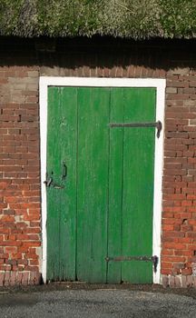 Old wooden green door in a barn with a thatched roof in the countryside (Altes Land) near Hamburg, Northern Germany.