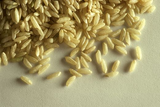 Closeup of grains of brown rice on white paper surface