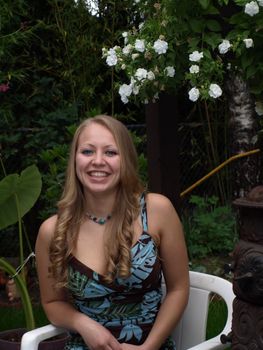 A smiling girl sits in a chair in the garden