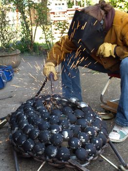 A female student welds an art project for school.