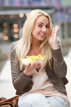 Beautiful young girl with french fries showing that she likes it
