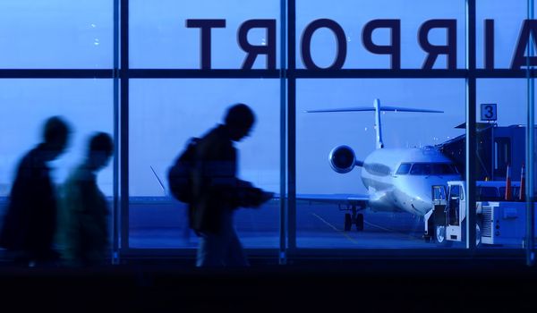 An abstract, motion blur image of people walking down a corridor to board an airplane.
