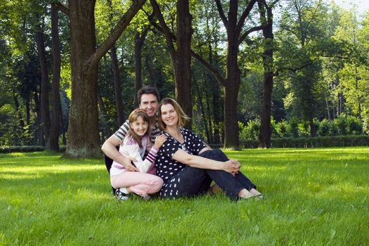 Lucky family on lawn in summer's forest.