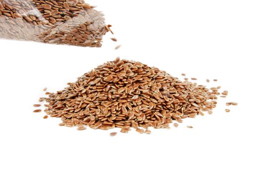 Pile of linseed being poured from a bag on a reflective white background
