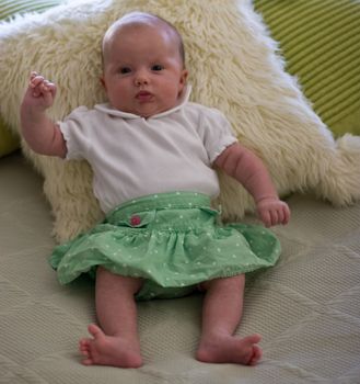 Cute caucasian girl dressed-up and trying to sit.