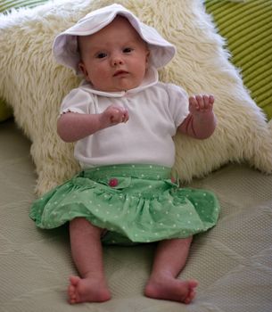 Cute caucasian girl dressed-up and trying to sit.