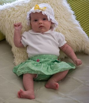 Cute caucasian girl dressed-up and trying to sit.