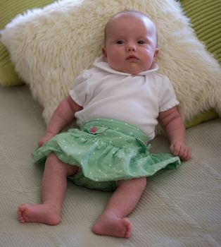 Cute caucasian girl dressed-up and trying to sit.