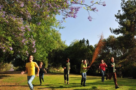 Group of six friends running with lots of enthusiasm in a park