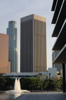 Tall skyscrapers tower above a plaza with fountains in downtown Los Angeles