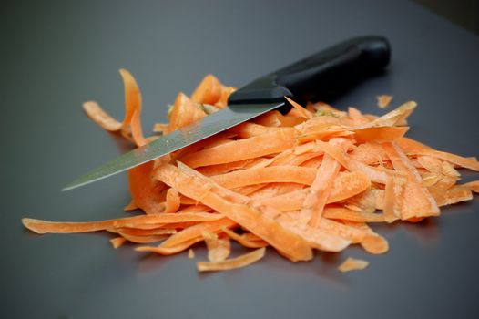 Carrot scraps and knife on a gray kitchen table