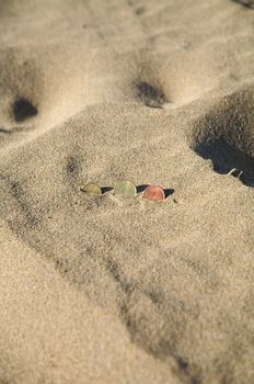 three euro coins at the sand of a beach
