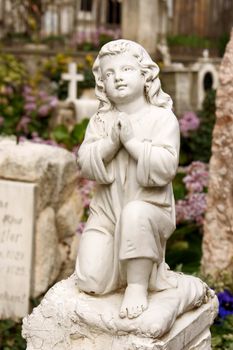 Marble little prayer statue in an old catholic cemetery