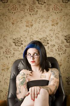 Pretty young woman with many tattoos in a leather chair