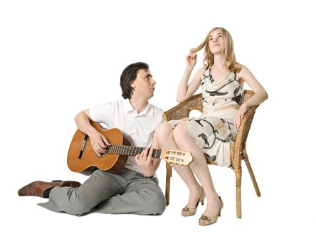 A blond girl and a man playing guitar for her