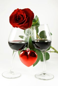 Red rose on two glasses and heart between them