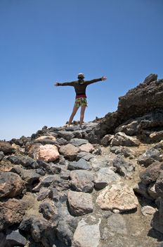 woman with cap open arms near the teide volcano in tenerife spain