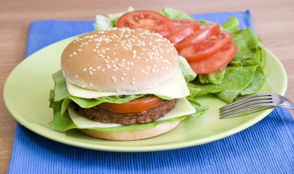 Fresh cheeseburger with lettuce, tomato and mayo and vegetables on the side