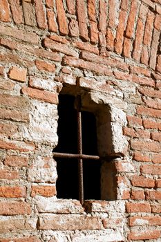 Ancient defense window on a fortress brick wall