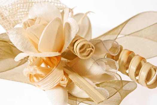 Close-up of a wedding favor composed of wooden rose and decorative elements and ribbons, isolated on white