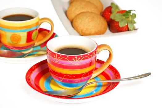 Two colorful cups of coffee, some biscuits and strawberries isolated on white