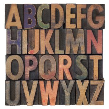 English alphabet (upper case) in vintage wooden letterpress type, stained by different color ink, flipped horizontally, isolated on white