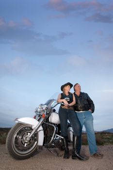 Man and woman with motorcycle in the desert at dusk