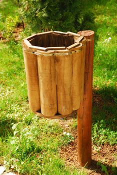 an empty wooden trash can in a green surrounding 