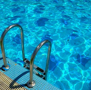 pattern of water of swimming pool with light in it and pool's stairway