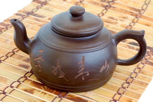classic chinese teapot of brown clay over bamboo mat