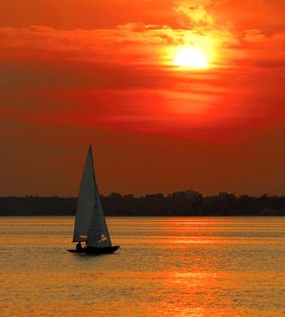 Beautiful seascape with yacht sailing into sunset.