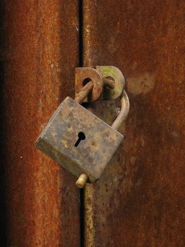 Old closed padlock on the rusty iron door