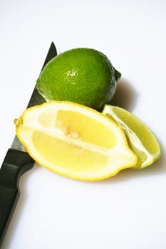 Fresh Lime and sliced Lemon on a light background with a knife.