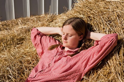 A country girl laying in a bale of straw