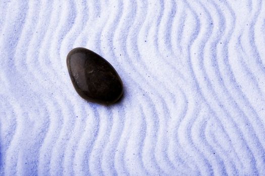Rock in a zen rock garden with blue sand
