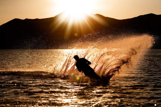 A male waterskiing in the evening sunset