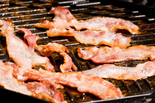 Bacon frying in a pan with lots of fat