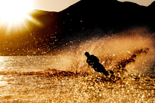 A male waterskiing in the evening sunset
