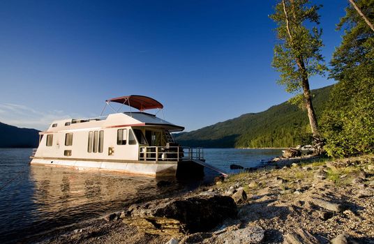 A luxury house boat beached on a beautiful lake
