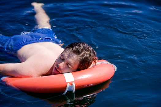 A swimmer laying exhausted on a life saving buoy