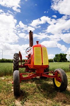 An old red retro tractor in a field