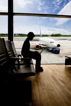 A young man using a laptop in an airport terminal