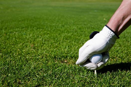 A golfer sets up a tee at a driving range