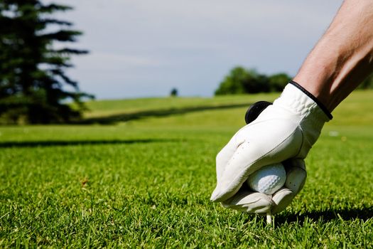 A golfer sets up a tee at a driving range