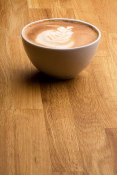 A cappuccino with latte art on a wooden table