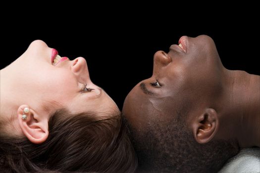 Two faces close up. Black man and white woman on a black background.