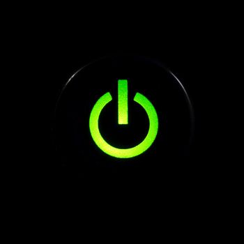 Glowing power button on black background
