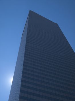 High modern skyscraper on a background of a blue sky and the sun.