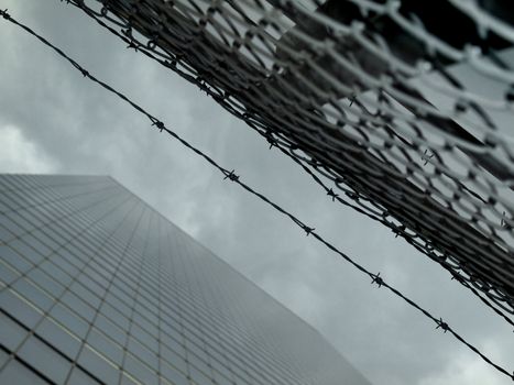 High modern skyscraper on a background of a cloudy sky with a fence and a barbwire.